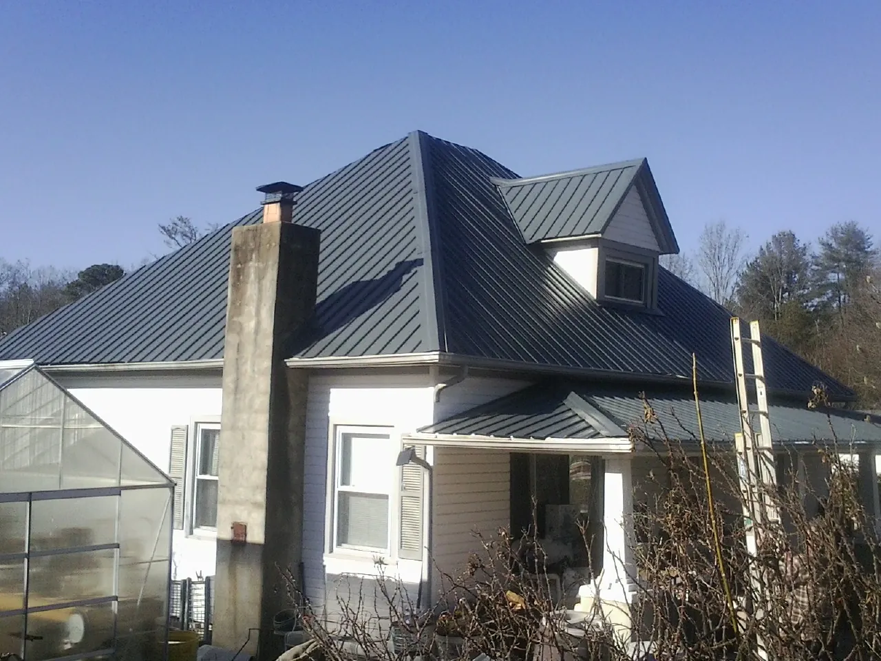 Dark blue standing seam metal roof on a white farmhouse with dormer — Slate & Tile Roof Repair by Roofing Brothers in Pawlet