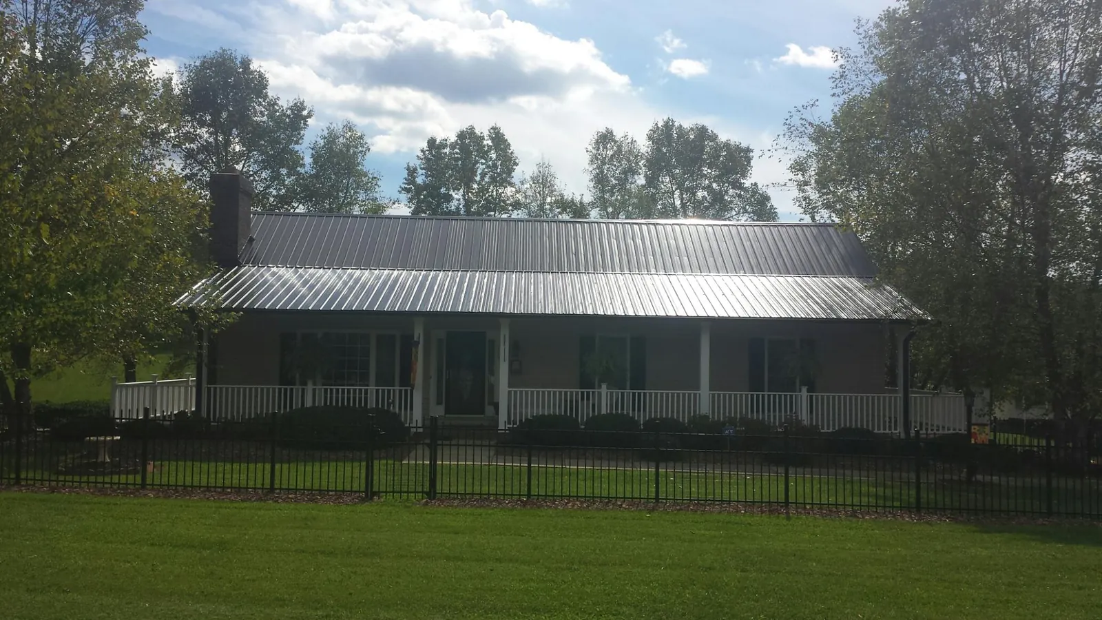 Gray metal roof on a brick ranch with a full width front porch — Gutter Guard Installation work by our crew in Pawlet