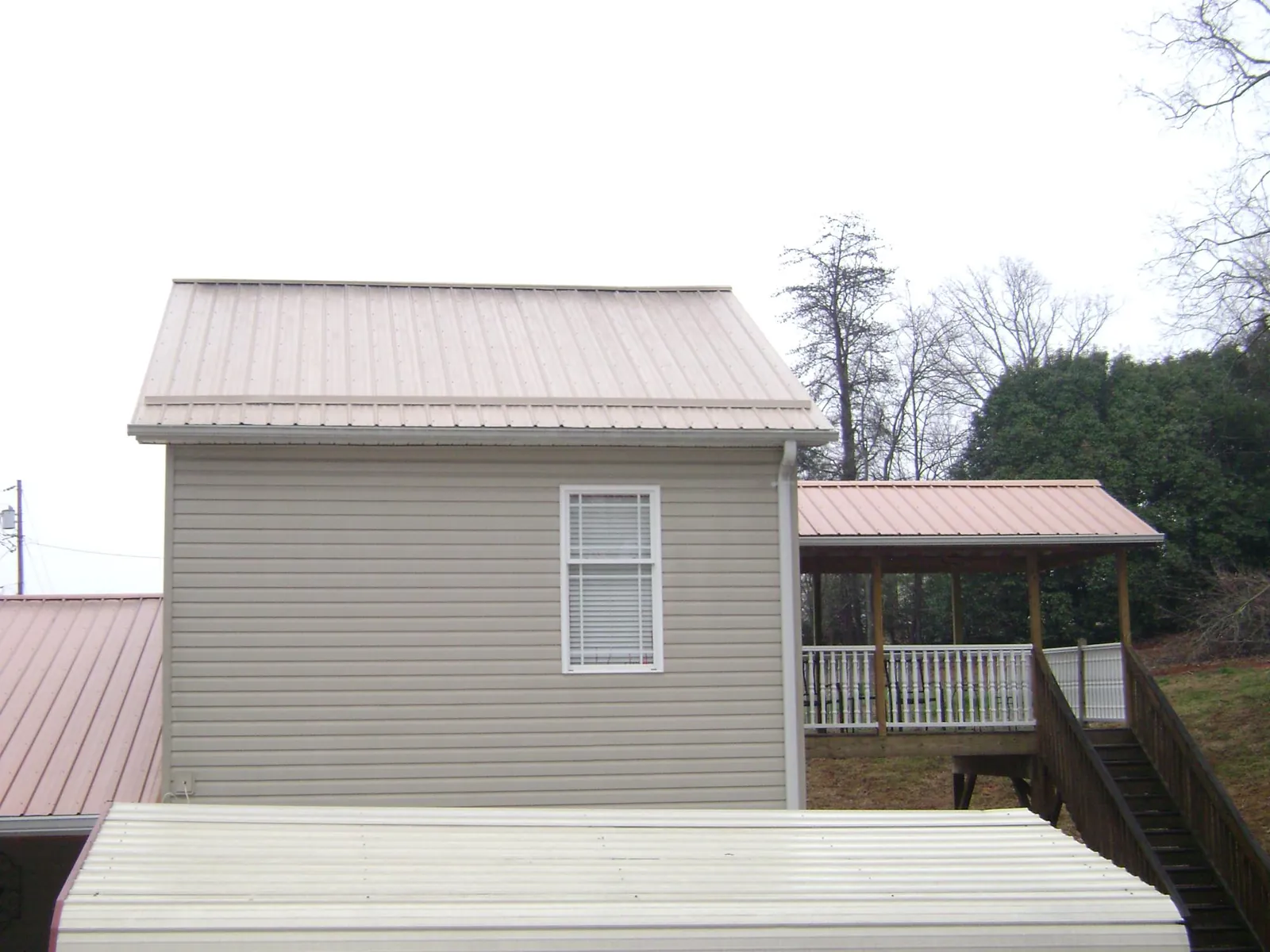 Tan metal roofs on a two story addition and attached porch, from a Roof Replacement job in Pawlet