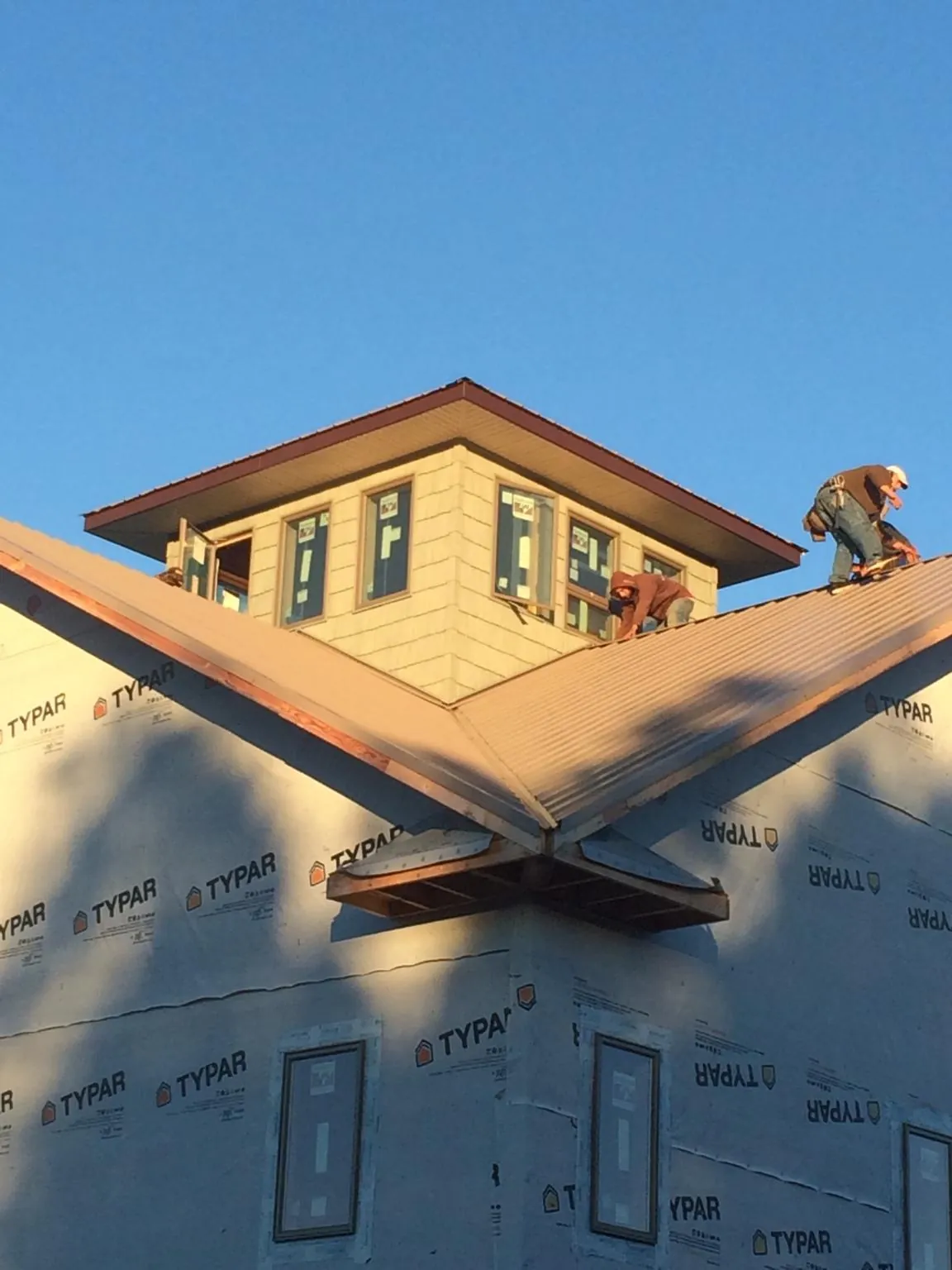 Roofers working around a rooftop cupola on a new metal roof at sunset — Roof Waterproofing in Pawlet by Roofing Brothers